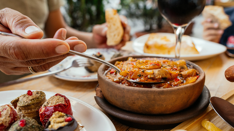 hand holding spoonful of mushroom soup next to red wine