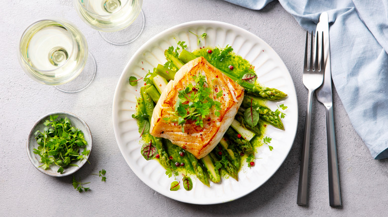 overhead shot of cod on a bed of greens with white wine