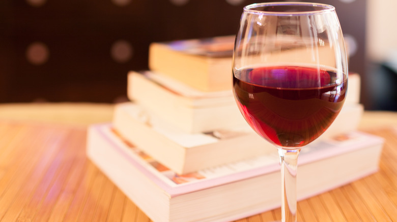 glass of red wine next to a small stack of books
