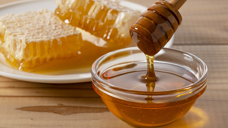 Honey in a bowl with honeycomb in the background