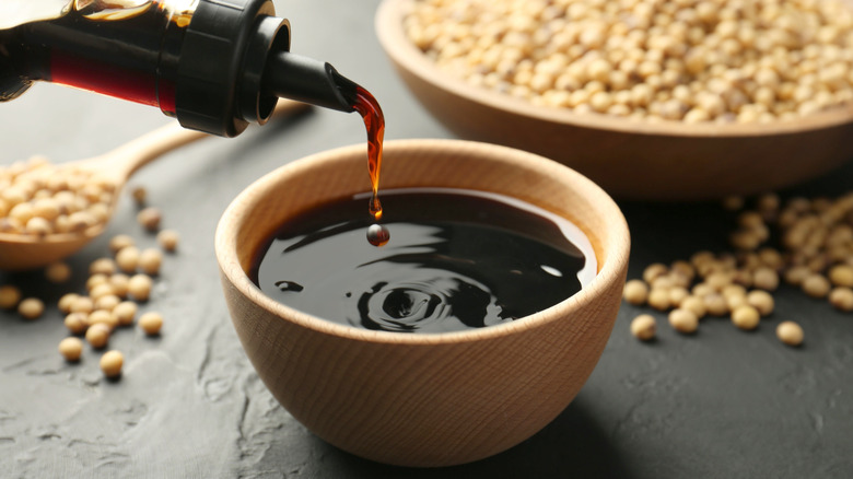Pouring soy sauce condiment from bottle into small bowl