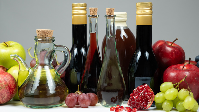 Bottles of vinegar surrounded by fruit