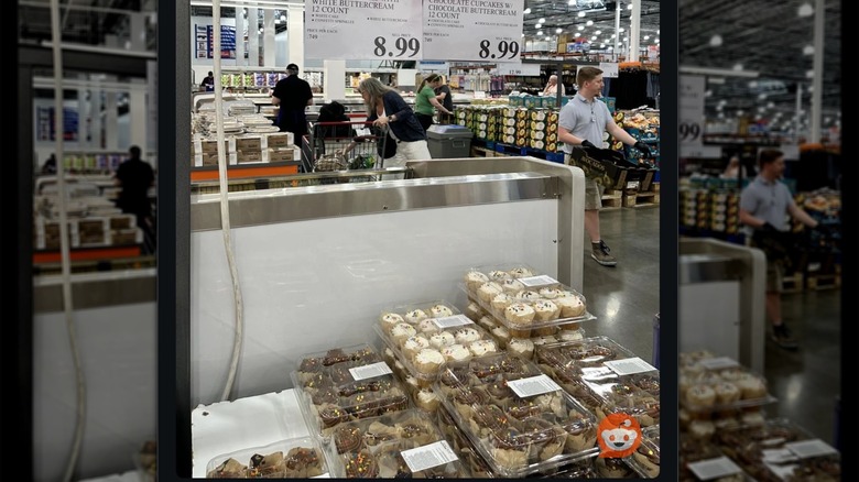 Chocolate and vanilla cupcakes stacked at Costco as shoppers walk around them.