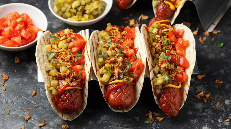 Row of hot dog tacos with various toppings