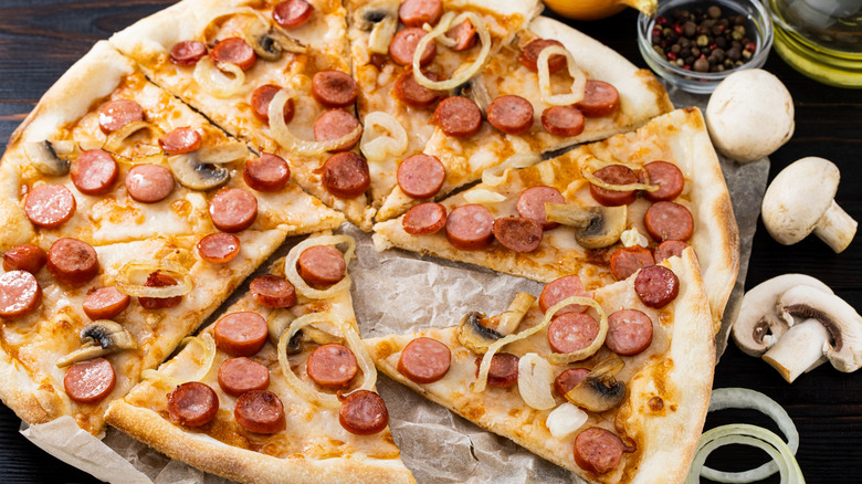 Pizza with sliced hot dogs, onions, and mushrooms
