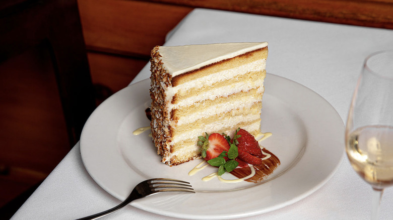 Ultimate Coconut Cake on a white plate placed on a white tablecoth