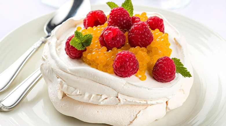 Pavlova topped with fruit on a white plate
