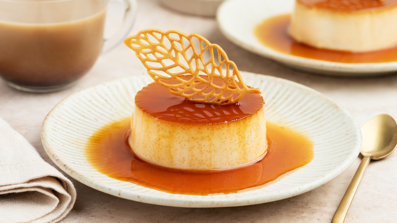 Creme caramel topped with a leaf cookie garnish on a white plate