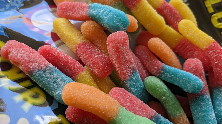 Trolli Sour Brite Crawlers gummies sit in a pile on top of product packaging
