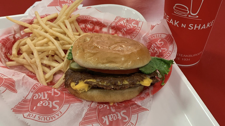 Steak N Shake burger with fries and a drink on red tabletop