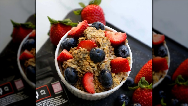 A bowl of PB+Berry overnight oats topped with strawberries and blueberries.