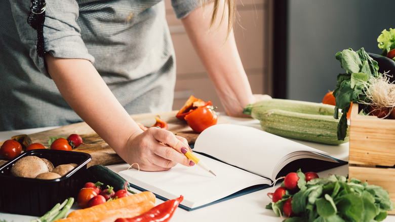 woman writing cooking notes in book