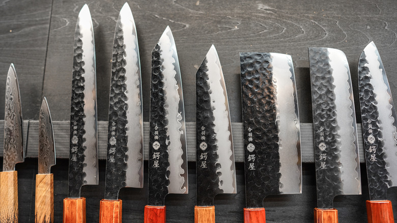 An assortment of Japanese knives on a magnetic strip.