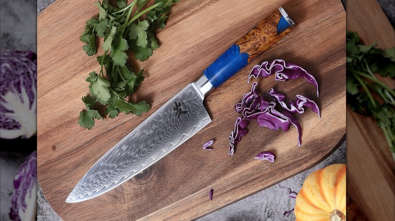 SAMCOOK Damascus Chef Knife,8 Inch Japanese Gyuto Knife on a cutting board with some cilantro and cabbage.