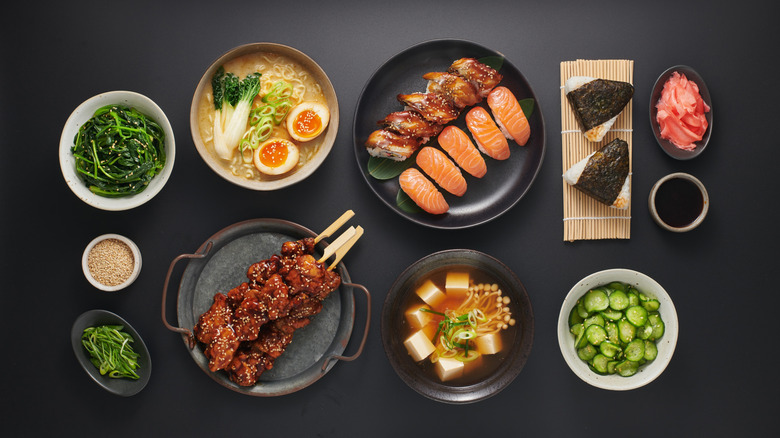 A variety of Japanese dishes sit on a black tabletop