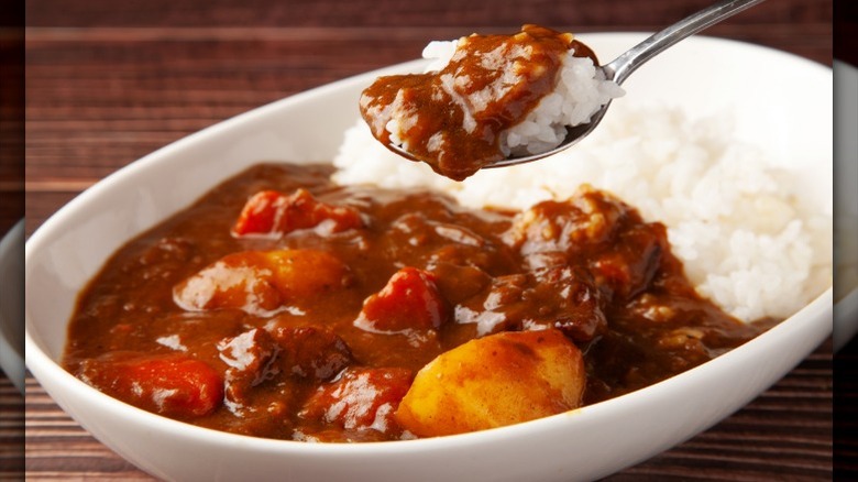 A bowl of Japanese curry and white rice is on a table.