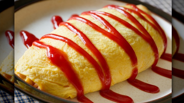 Omurice, an omelet filled with rice, sits on a plate and is garnished with ketchup