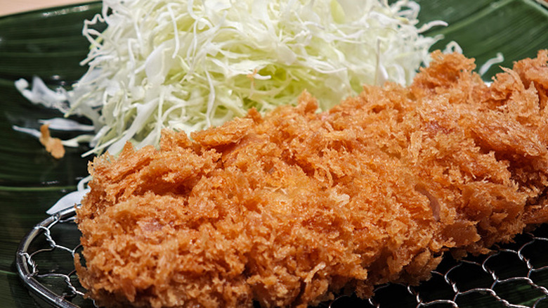 A Tonkatsu cutlet and a pile of shredded cabbage are on a plate.