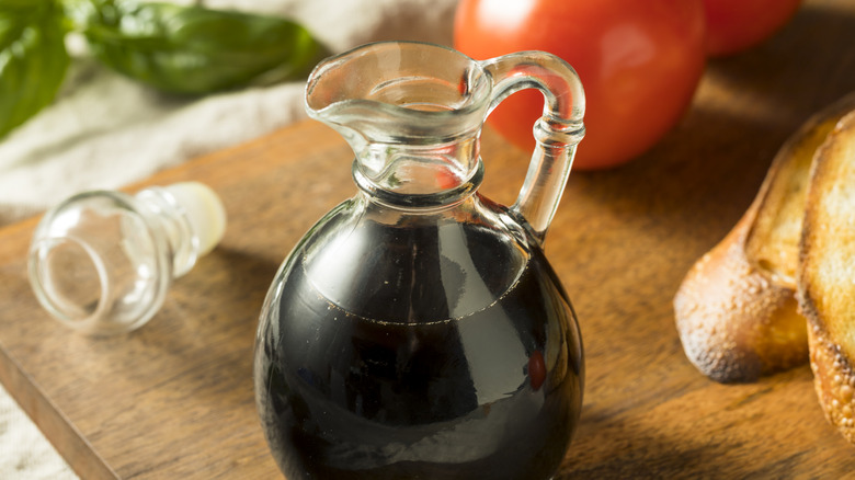 balsamic vinegar on wood board with tomatoes and bread