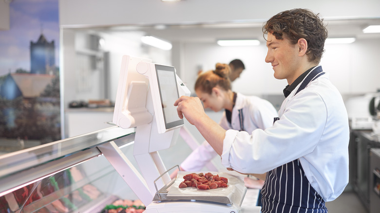Smiling butcher weighing cubed meat
