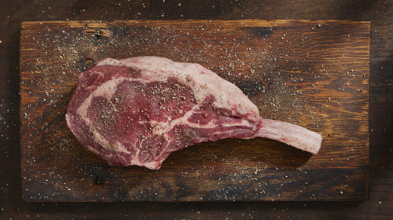 Seasoned rib steak on wooden board