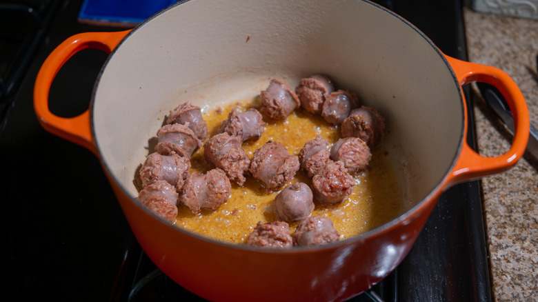 Sausage sizzling in oil in a Dutch oven