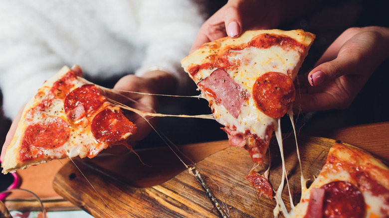 hands holding slices of pizza