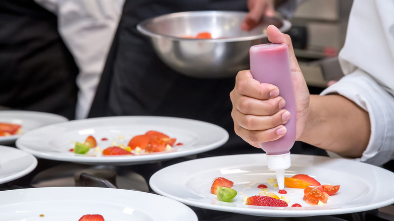 Chef garnishing plate with squeeze bottle