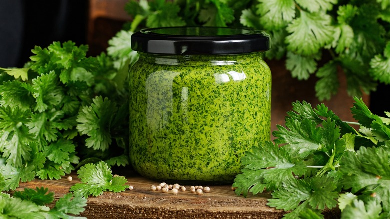 pesto in a glass jar resting on a wooden cutting board