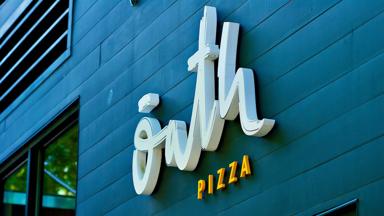 Oath Pizza signage affixed to blue slated wall