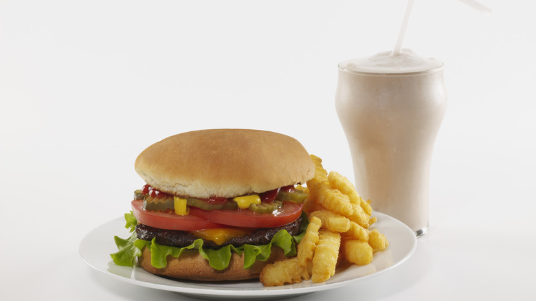 Cheeseburger plated with crinkle-cut fries beside a milkshake