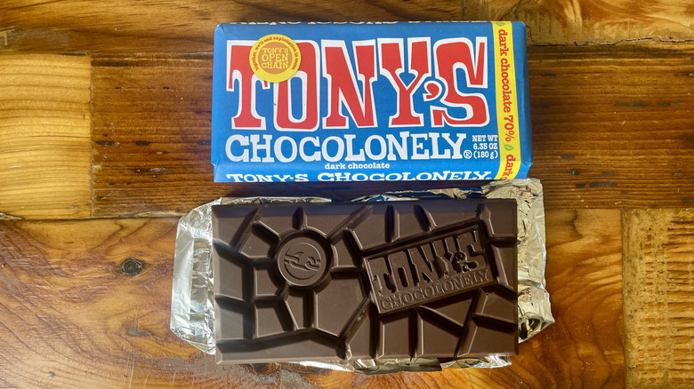 An unwrapped Tony's Chocolonely 70% Dark Chocolate Bar lying on a wooden table top