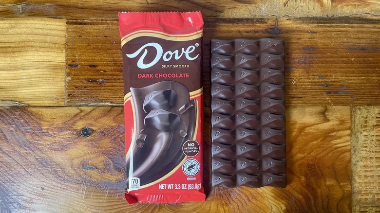 An unwrapped Dove Dark Chocolate Bar lying on a wooden table top