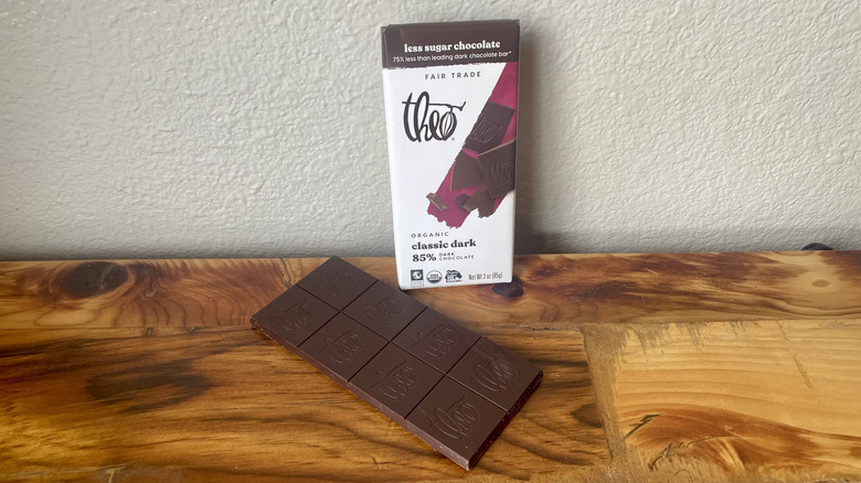 An unwrapped Theo Fair Trade Pure Organic 85% Dark Chocolate Bar on a wooden table top