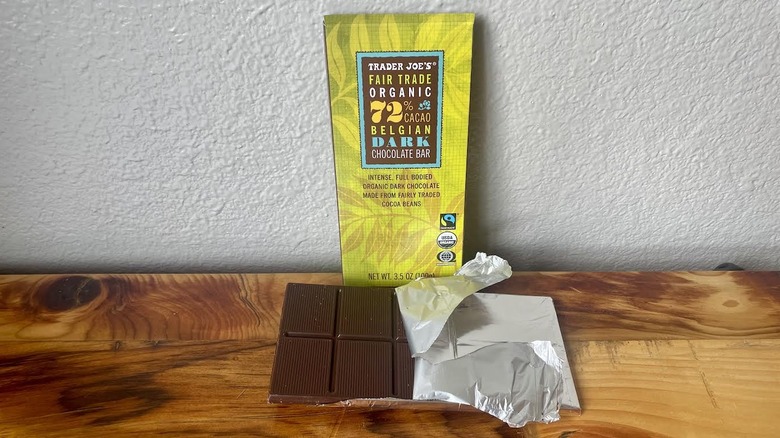 A partially unwrapped Trader Joe's Organic 72% Cacao Belgian Dark Chocolate Bar on a wooden table top