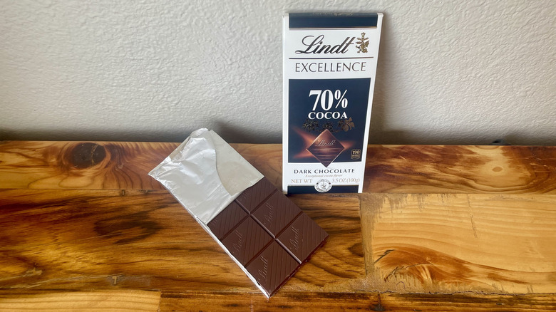 An unwrapped Lindt Excellence 70% Cacao Dark Chocolate Bar on a wooden table top