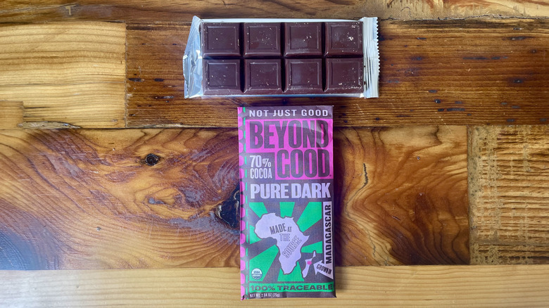 An unwrapped Beyond Good Organic 70% Cocoa Pure Dark Chocolate Bar lying on a wooden table top