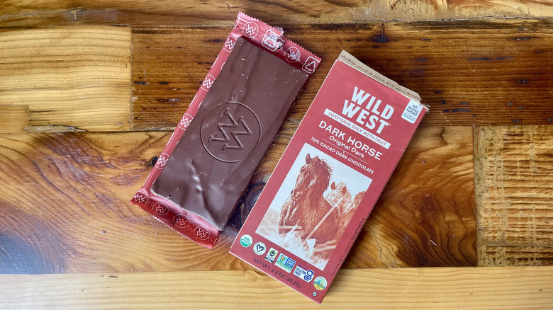 An unwrapped Wild West Chocolate Organic 70% Cacao Dark Chocolate Bar lying on a wooden table top
