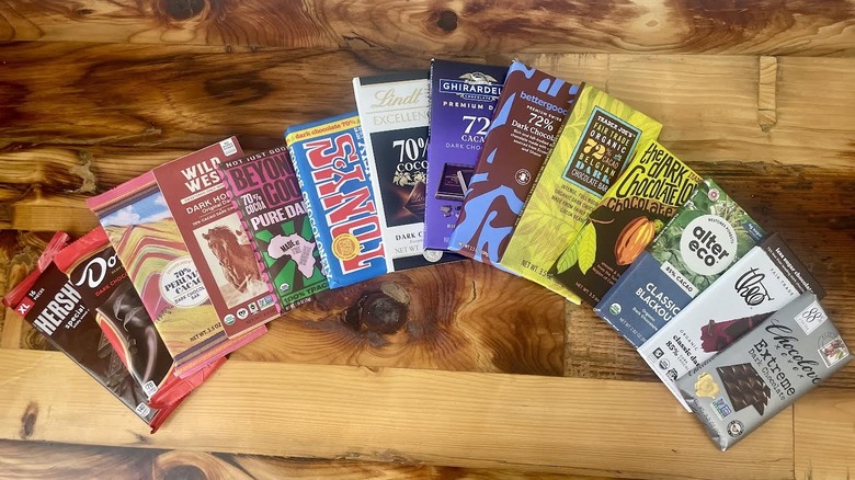 A collection of store-bought dark chocolate bars fanned out on a wooden table top