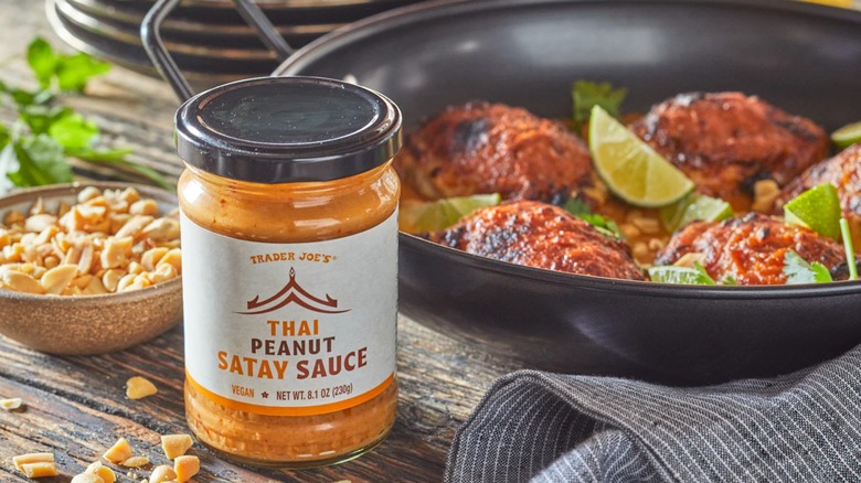Trader Joe's Thai Peanut Satay Sauce with a pan of grilled chicken in the background.