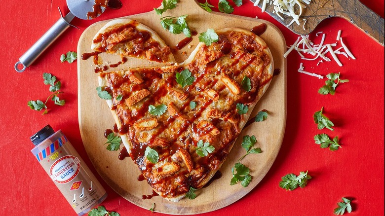 Yangnyeom sauce from Trader Joe's next to a heart-shaped fried chicken pizza.