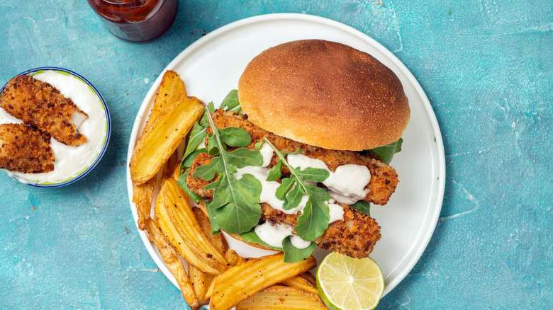 Fish sandwich on plate with potato wedges