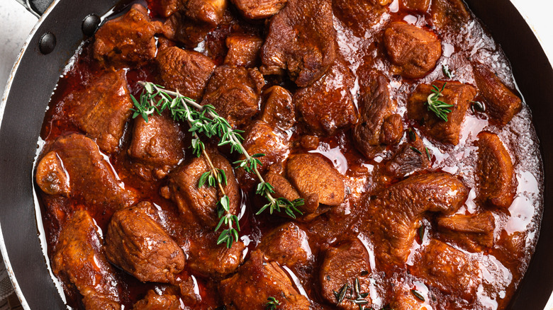 close up of meat braising in liquid
