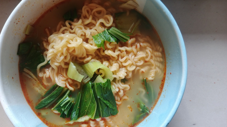 overhead shot of a bowl of noodles in broth with greens