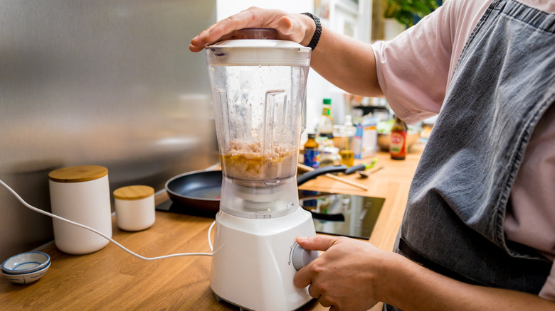 Person blending beans in countertop appliance