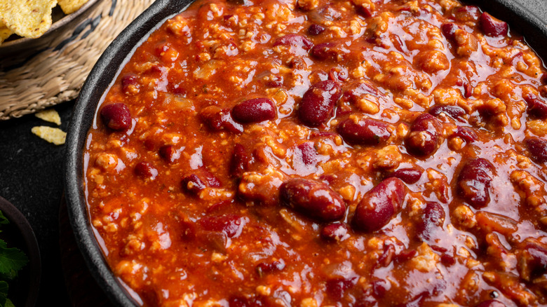 Chili with beans in a cast iron dish near tortilla chips