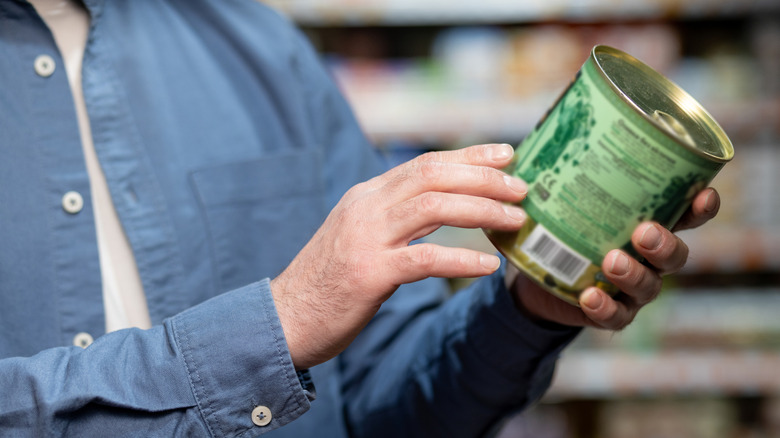 Canned item in the hands of a customer in a blue shirt