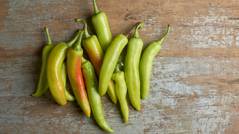A small pile of yellow, green, and reddish banana peppers