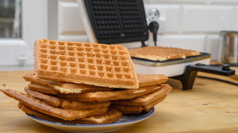 Pile of waffles next to waffle cooking