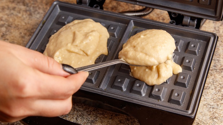 Spooning waffle batter into waffle iron